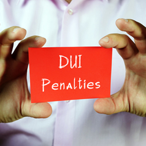 A person holding a card with the text "DUI Penalties"